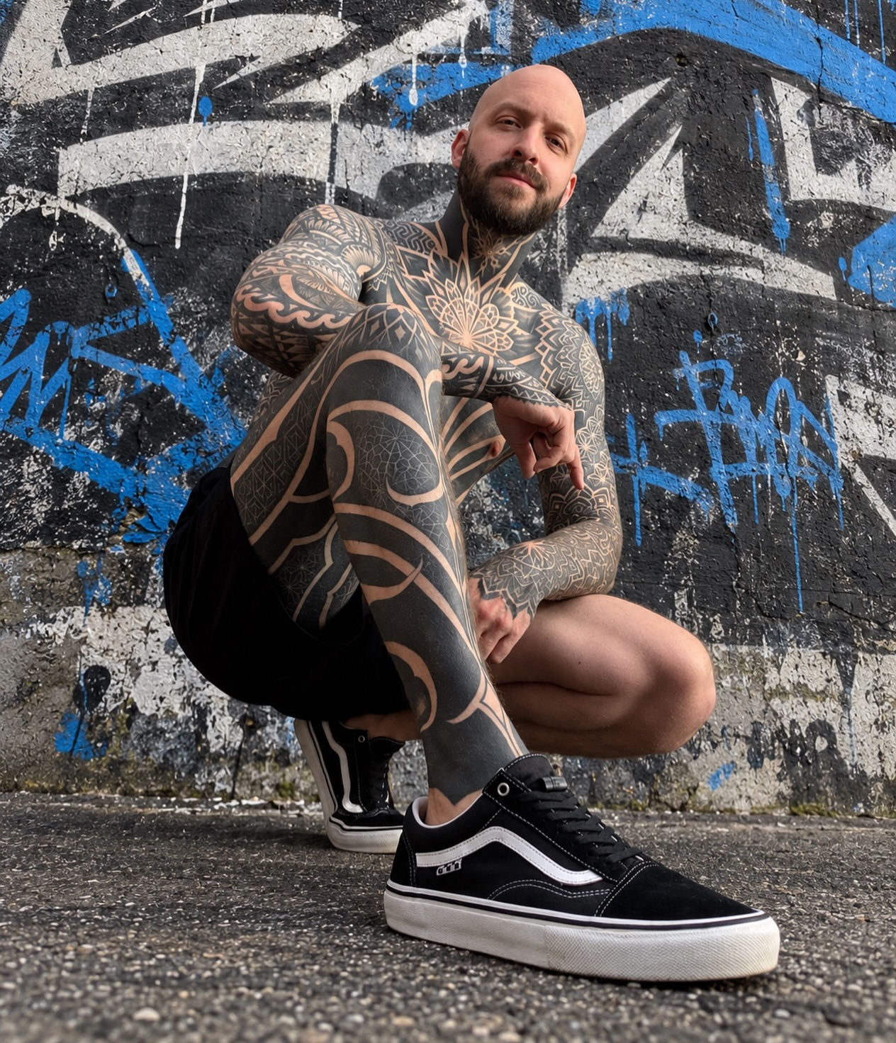 Kevin mit Blackwork-Tattoos vor einer Graffiti-Wand